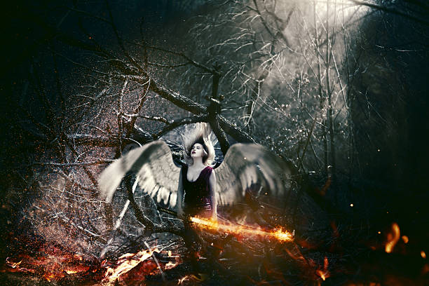 fallen angel seductive woman in the woodland with wings and fire sword, with her head in the wind, eyes closed.surreal conceptual photo. vampire woman stock pictures, royalty-free photos & images