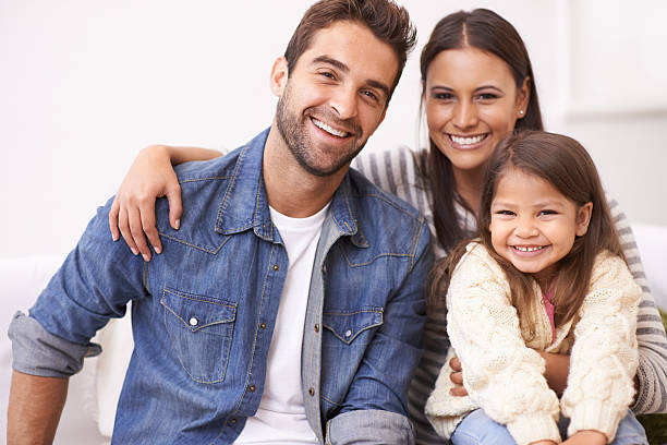They treasure each other Portrait of a happy young family sitting together at home young family photos stock pictures, royalty-free photos & images