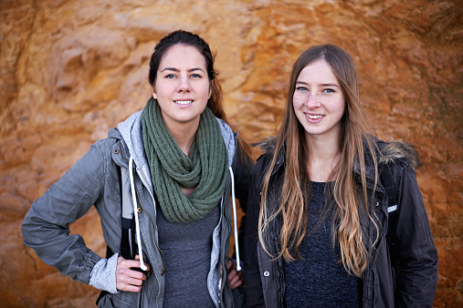 Portrait of two attractive young female hikers standing by a rockface