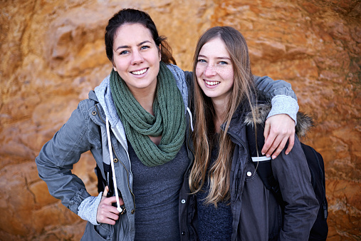 Portrait of two attractive young female hikers standing by a rockface