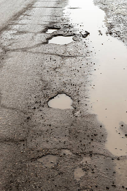 istock Large Pot Holes on a Rain Soaked Road 524881876