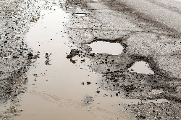 istock Large Pot Holes on a Rain Soaked Road 524882218