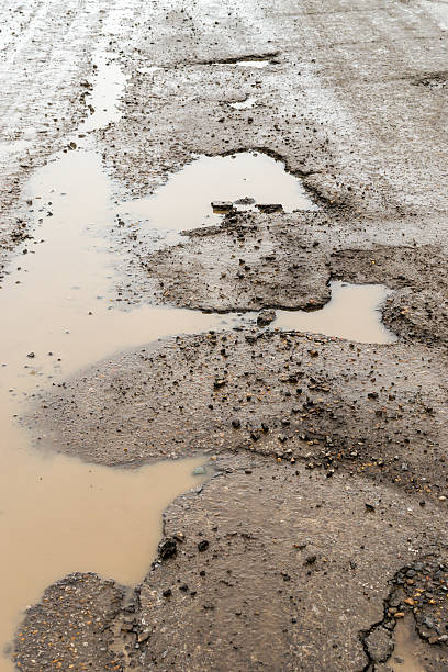 istock Large Pot Holes on a Rain Soaked Road 524882444