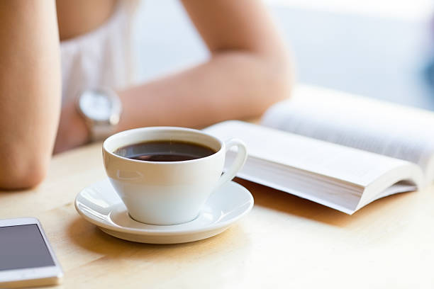 Girl reading a book and drinking coffee at a cafe