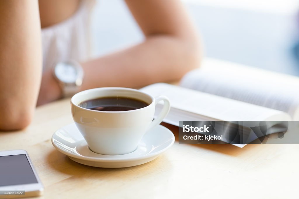 Woman reading book and drinking coffee at cafe Girl reading a book and drinking coffee at a cafe Book Stock Photo