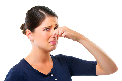 Studio shot of a young woman holding her nose isolated on white