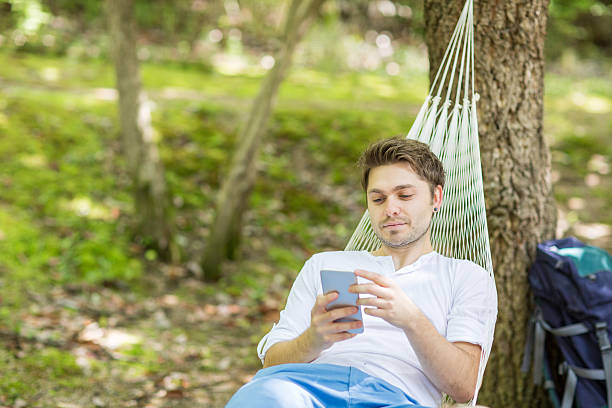 istock Mid-adult man using a smartphone in a hammock 524885840