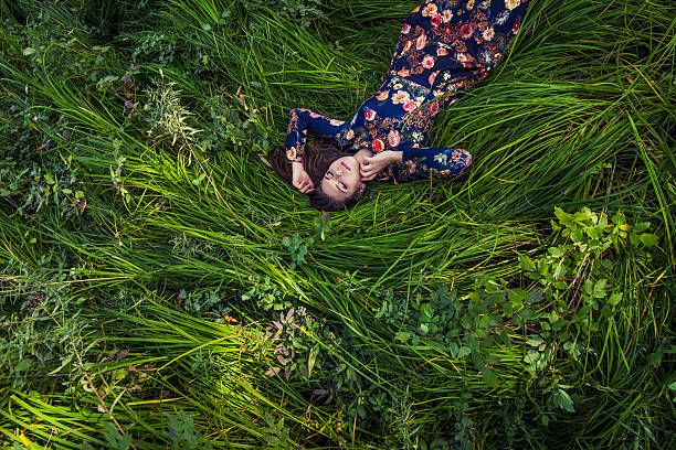 mujer joven hermosa en un vestido caer en el césped - on top of grass scenics field fotografías e imágenes de stock