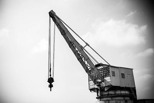 Detail of an old port crane against a cloudy sky. Toned.