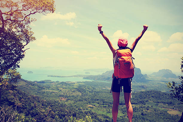istock cheering successful woman hiker open arms at mountain peak 524890452