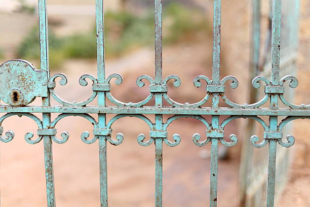 A wrought iron gate and archway are covered in ivy with an old glass lantern at the center of the arch in historic Savannah, Georgia.