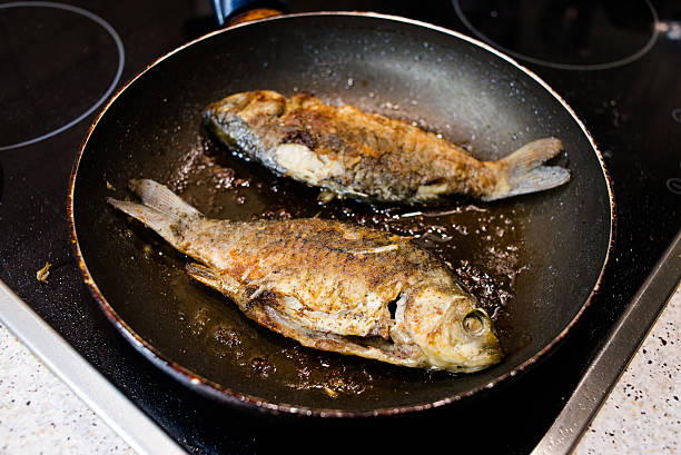 fresh fried fish in a frying pan on the cooker