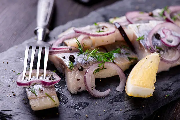 Photo of Sliced herring on a black slate plate