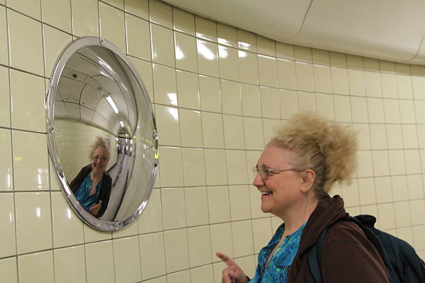 Woman Looking In A Convex Mirror Woman looking in a convex lens in the Paris subways used for pedestrian traffic control convex stock pictures, royalty-free photos & images