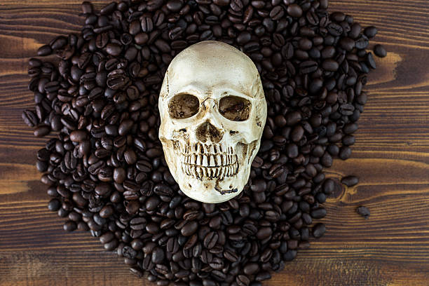 istock Skull and coffee beans isolated on wood background. 524899346