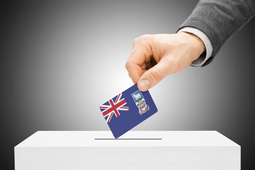 Voting concept - Male inserting flag into ballot box - Falkland Islands