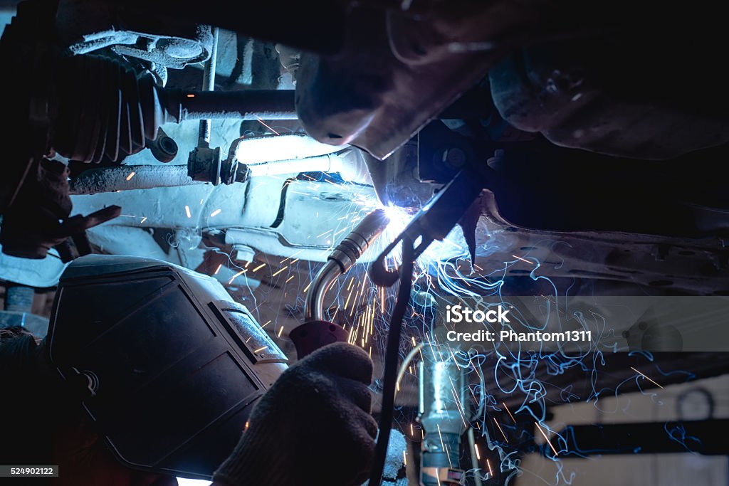 Welder working in protective mask Welder in a protective mask welds metal frame Car Stock Photo