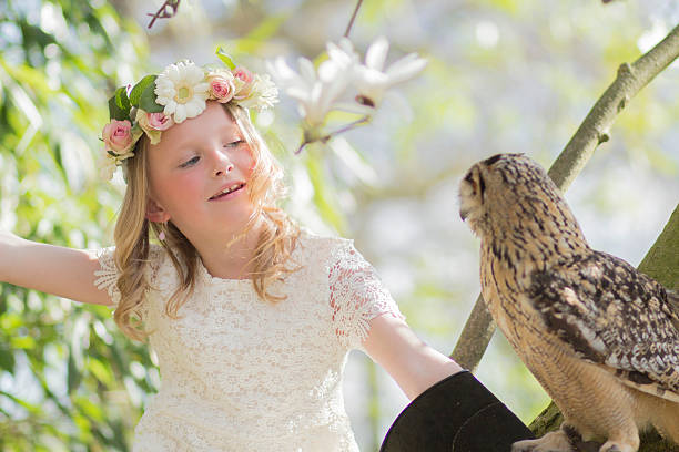 fille blonde avec un hibou dans un arbre de magnolia - formal garden ornamental garden child single flower photos et images de collection