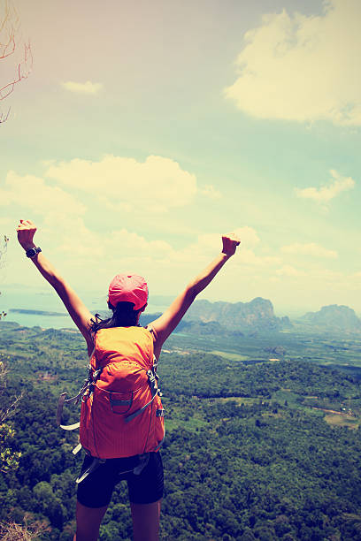 istock cheering successful woman hiker open arms at mountain peak 524903474