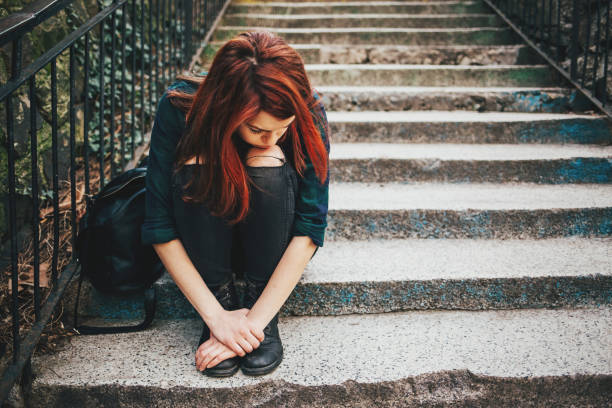 Sad lonely girl sitting on stairs Depressed young woman sitting on stairs outdoors, with copy space drug abuse stock pictures, royalty-free photos & images