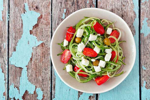 istock Greek Salad with cucumber noodles, overhead view on rustic wood 524905996