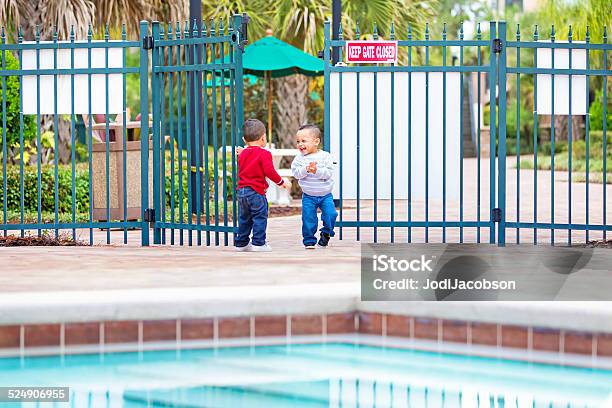 Terrible Twos Twin Boys Get Into A Gate To Pool Stock Photo - Download Image Now - 18-23 Months, 2-3 Years, African Ethnicity