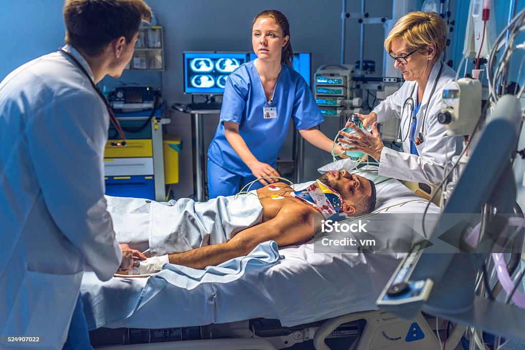 Medical team doing the CPR activites on injuried patient Female doctor holding a resuscitation bag on the face of a patient in emergency room. Emergency Room Stock Photo