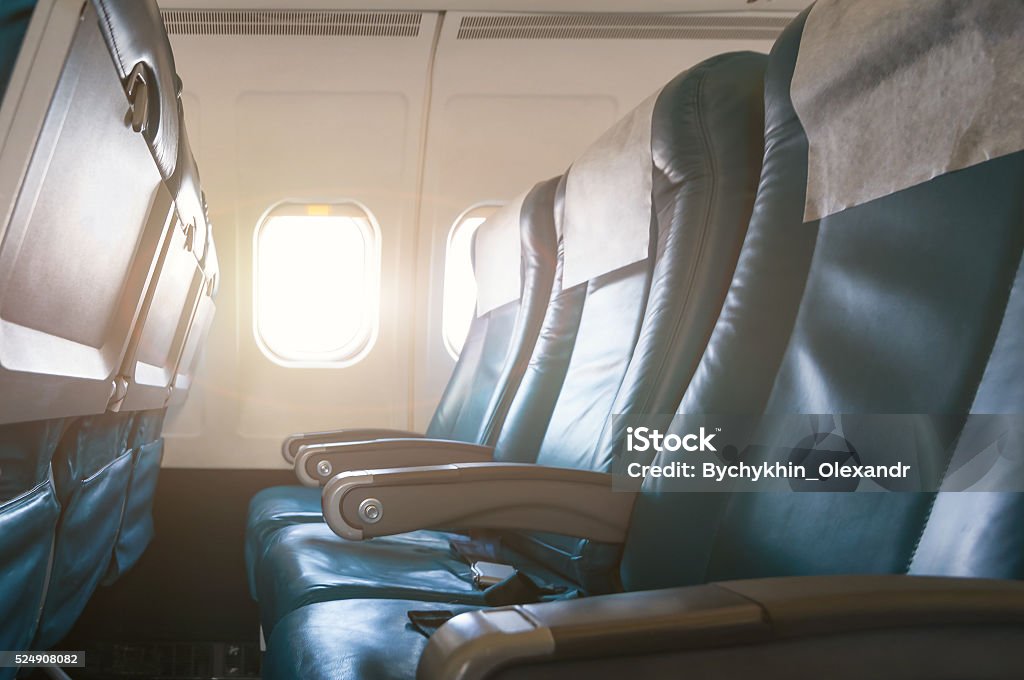 Interior of airplane with empty seats and sunlight at the Interior of airplane with empty seats and sunlight at the window. Travel concept. Airplane Stock Photo