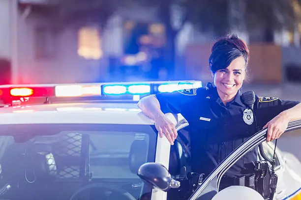 Photo of Female police officer standing next to patrol car