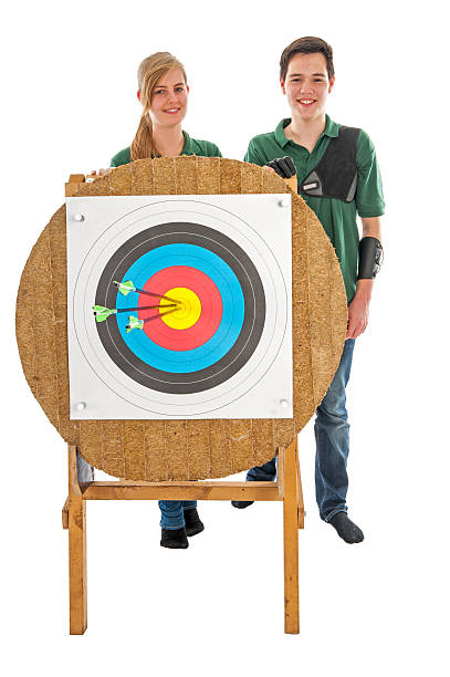 Girl and boy standing behind archery target stock photo