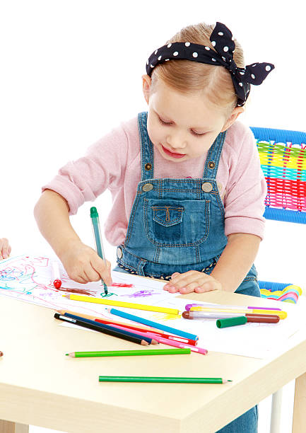 istock Charming little girl draws with markers while sitting at table. 524942117