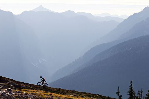 A male mountain bike rider rides up a single track trail in British Columbia, Canada.