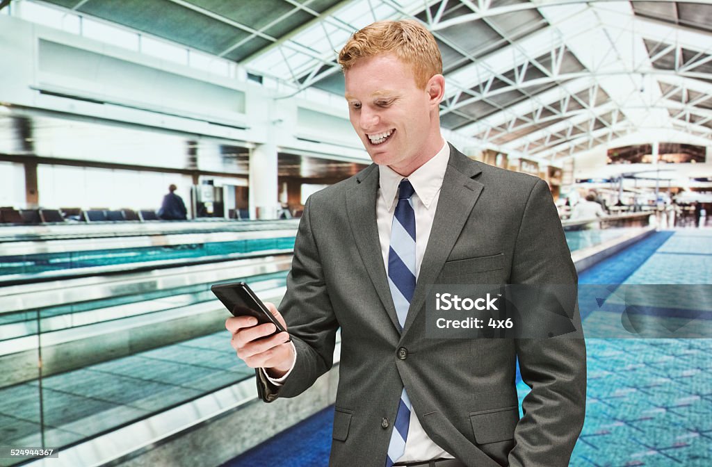 Smiling businessman using mobile in front of airport Smiling businessman using mobile in front of airporthttp://www.twodozendesign.info/i/1.png 25-29 Years Stock Photo