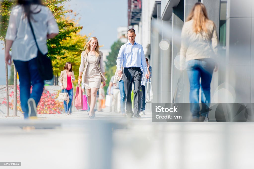 Couple on Crowded City Street After Shopping Crowd of people walking on a street, blurred foreground. Pedestrian Zone Stock Photo