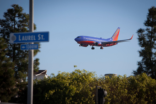 San Diego, California USA - November 20, 2014: A Southwest Airlines jet approaches San Diego International Airport. The airport's close proximity to downtown San Diego means planes make their approach very close to homes and businesses.