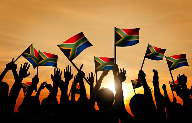 group of people waving south african flags in back lit - zuid afrika stockfoto's en -beelden