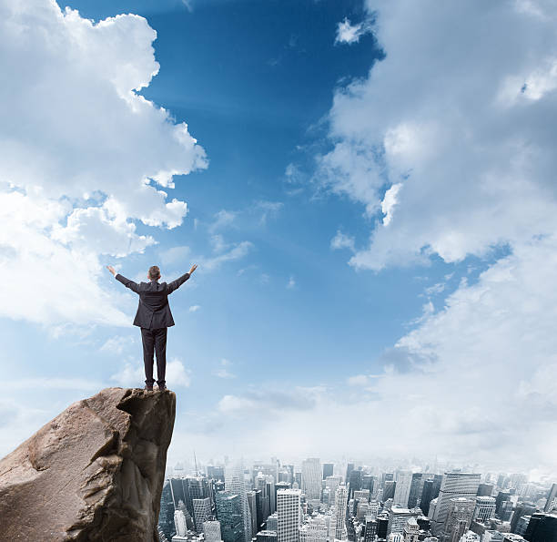 istock businessman standing on edge of rock mountain 524998695