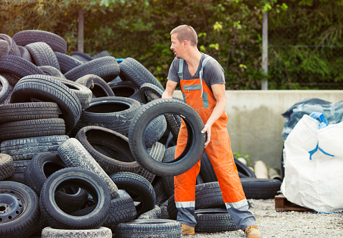 Manual worker at a waste recycling center sorting old tires