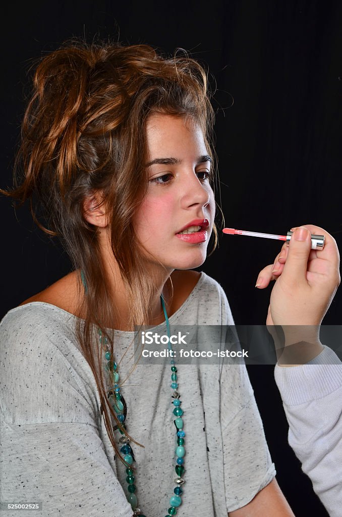 Photo session preparation Professional makeup of teenage brunette girl during preparation for photo session, studio shot against black background Applying Stock Photo