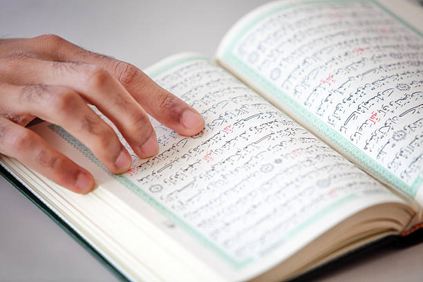 istock Human hand on the Holy Koran Book 525014470