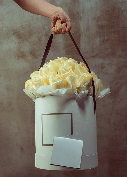 Hand holding a luxury bunch of white roses with empty card for you text.
