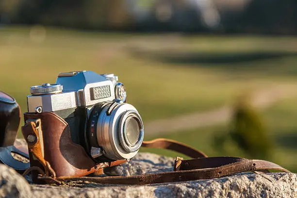 Retro film photocamera on stone outdoors