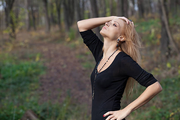 Pretty mysterious woman in black dress posing in the forest