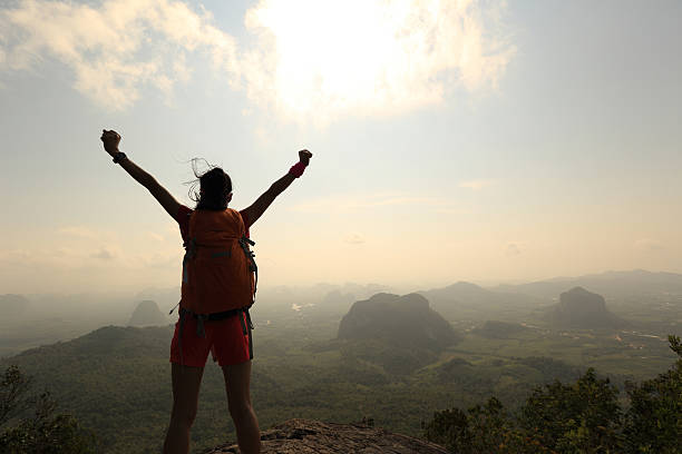 istock cheering successful woman hiker open arms at mountain peak 525018230