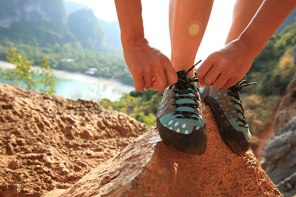istock one young woman rock climber tying shoelace on rock 525020558