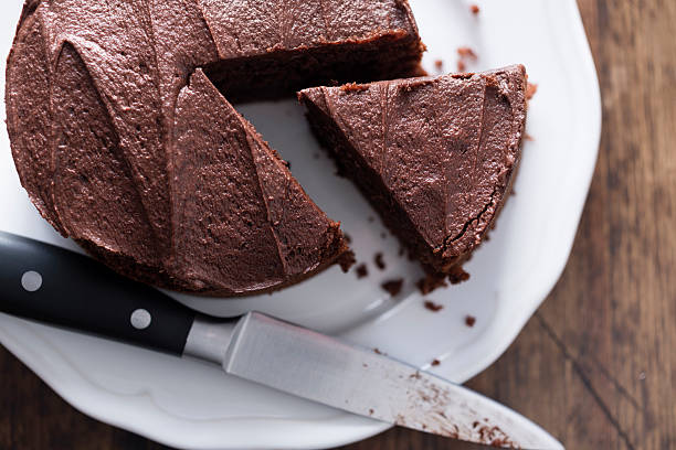 Chocolate Cake Whole Chocolate Cake on a white plate, with knife and piece sliced. chocolate cake photos stock pictures, royalty-free photos & images
