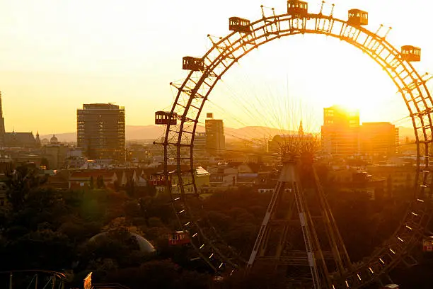 A big wheel at sunset with cityscape in background