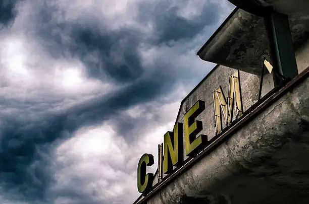 old abandoned closed movie theater under stormy sky