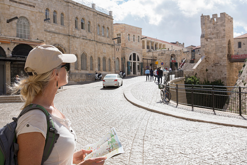 Woman looks at tourist map on city street, Jaffa Gate
