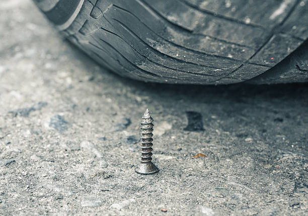 Sharpen metal screw nail nearly to puncture into wheel tire, selective focus (colored filter effect)